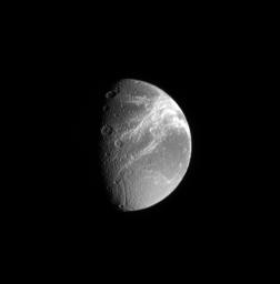 Saturn's moon Dione's defining feature, the fractures on its trailing side, shine brilliantly in this image captured by NASA's Cassini spacecraft.