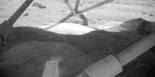 NASA's Phoenix Mars Lander shows the martian surface beneath it. The light feature below the leg is informally called 'Holy Cow.'