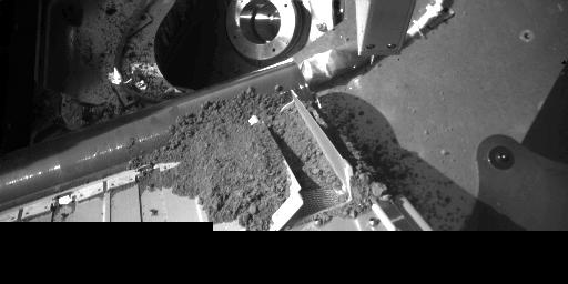 NASA's Phoenix Mars Lander is shown with one set of oven doors open and dirt from a sample delivery. A portion of the dirt sample entered the oven via a screen for analysis.
