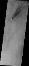 This image from NASA's Mars Odyssey shows a windstreak located on the volcanic flows east of Pavonis Mons. The multiple tail ends indicate the direction of the wind has changed over time. The darkest tail is the most recent.