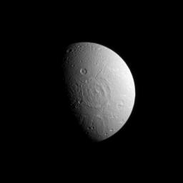 A broad impact basin hints at Dione's split personality in this image from NASA's Cassini spacecraft. Dione's leading hemisphere is heavily cratered by impacts while its trailing hemisphere features bright ice cliffs created by tectonic fractures.