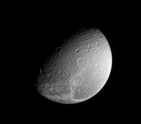 NASA's Cassini spacecraft looks down on the north pole of Saturnian moon Dione and the fine fractures that cross its trailing hemisphere.