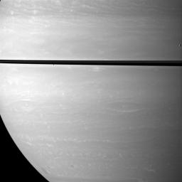 While studying Saturn's atmosphere, NASA's Cassini spacecraft happens to catch a view of two small, icy satellites. Mimas drifts past on the far right of the image. Janus appears as a black dot just below the rings near the center of the image.