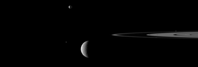 A gaggle of moons parade around Saturn's rings in this image from NASA's Cassini spacecraft in which the large moon Rhea passes in front of the small moon Janus. Go to the Photojournal to view the animation.
