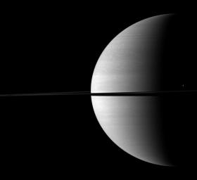 The moon Tethys stands out as a tiny crescent of light in front of the dark of Saturn's night side. Tethys can be seen above the ringplane on the far right of this NASA Cassini spacecraft image.