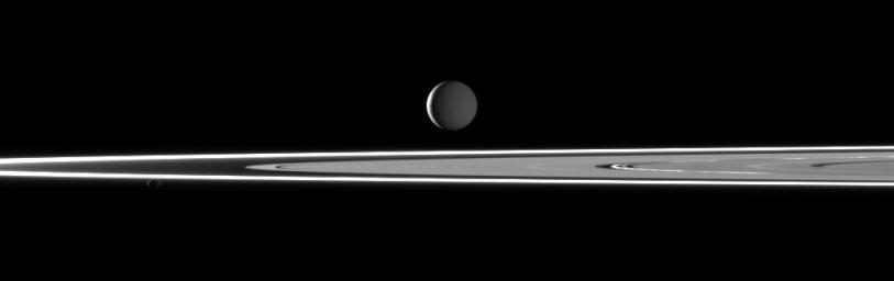 In this image taken by NASA's Cassini spacecraft two light sources illuminate Saturn's highly reflective moon Enceladus featuring bright rings and the small moon Pandora in the foreground.