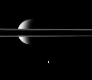 Saturn's rings, partially darkened by the planet's shadow, cut a striking figure before Saturn's largest moon, Titan. The moon Mimas is near the bottom of this image taken by NASA's Cassini spacecraft.