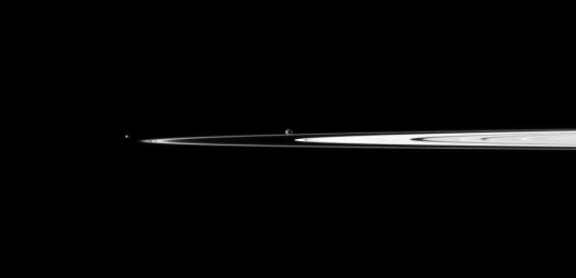 A pair of Saturn's small moons orbit near the planet's rings, which appear well illuminated in this view captured by NASA's Cassini spacecraft. Janus is near the center of the image and Pandora is on the left.