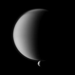 Crisp details on Dione contrast with the haziness of Titan in image from NASA's Cassini spacecraft of a pair of Saturn's moons. Smaller Dione is at the bottom of the image, and that moon's wispy terrain is visible.