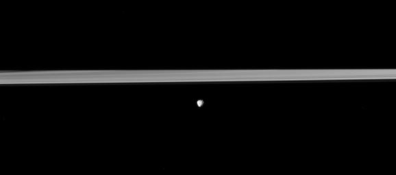 Saturn's moon Janus orbits in front of the rings, which are partially darkened by the shadow of the planet in viwe from NASA's Cassini spacecraft. Saturn's shadow obscures about half the rings.