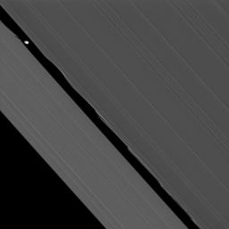 NASA's Cassini spacecraft captures here one of its closest views of Saturn's ring-embedded moon Daphnis. Seen at the upper left of this image, Daphnis appears in the Keeler Gap near the edge waves it has created in the A ring.