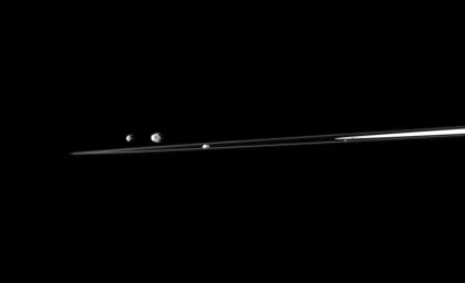 A quartet of Saturn's moons are shown with a sliver of the rings in this view from NASA's Cassini spacecraft. From left to right in this image are Epimetheus, Janus, Prometheus, and Atlas.