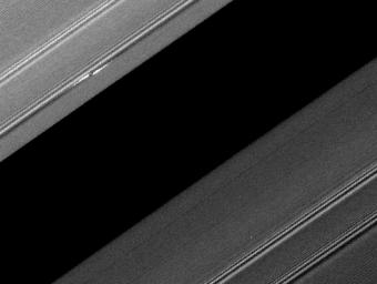A propeller-shaped structure created by an unseen moon is brightly illuminated on the sunlit side of Saturn's rings in this image obtained by NASA's Cassini spacecraft. The moon, which is too small to be seen, is marked with a red arrow.