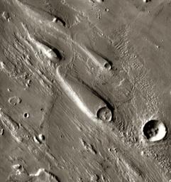In Ares Vallis, teardrop mesas extend like pennants behind impact craters, where the raised rocky rims diverted the floods and protected the ground from erosion. This image is from NASA's Mars Odyssey, one of an 'All Star' set.