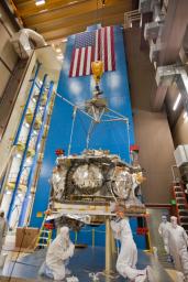 Technicians lift NASA's Juno spacecraft onto a dolly prior to the start of a round of acoustical testing.