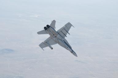 A NASA Dryden Flight Research Center F/A-18 852 aircraft performs a roll during June 2011 flight tests of a Mars landing radar. A test model of the landing radar for NASA's Mars Science Laboratory mission is inside a pod under the aircraft's left wing.