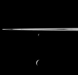 A pair of Saturn's moons appears as if hung below the planet's rings in this view from NASA's Cassini spacecraft. Enceladus appears just below the rings here, near center, Tethys is near bottom center, and Tethys is closer to Cassini than is Enceladus.