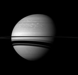 Saturn's rings cast wide shadows on the planet, and the shadow of a moon also graces the gas giant in this scene from NASA's Cassini spacecraft. The moon Enceladus is not shown in this view, but it does cast a small, elongated shadow.