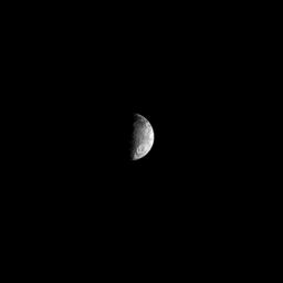 A large crater can be seen in the southern hemisphere of Saturn's two-tone moon Iapetus. Lit terrain seen here is on the trailing hemisphere while the leading hemisphere is extremely dark and whose trailing hemisphere is as white as snow.