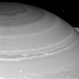 Saturn and its north polar hexagon dwarf Mimas as the moon peeks over the planet's limb. Saturn's A ring also makes an appearance on the far right. Mimas is 246 miles (396 kilometers) across.