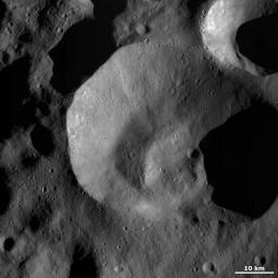 This image from NASA's Dawn spacecraft shows Caparronia crater on asteroid Vesta, an unusually shaped, irregular rim that is sharp and fresh in some areas and more rounded and degraded in others.