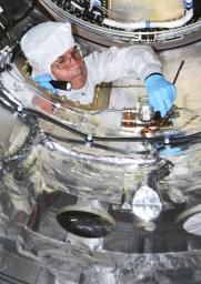 A spacecraft technician is performing closeout work inside the fairing that will be installed around NASA's Nuclear Spectroscopic Telescope Array (NuSTAR) spacecraft in a processing facility at Vandenberg Air Force Base in California.