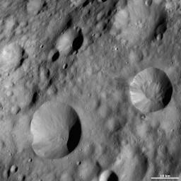 This image from NASA's Dawn spacecraft is located in Lucaria Tholus quadrangle, in Vesta's northern hemisphere. Around Publicia's rim are many alternating streaks of bright and dark material tumbling down towards its center.