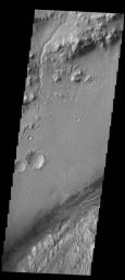 This image from NASA's 2001 Mars Odyssey spacecraft shows the northwestern floor and rim of Gale crater on Mars. A channel dissects the rim, and the edge of the central mound is visible in the bottom right corner.