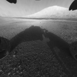 This image taken by NASA's Curiosity shows what lies ahead for the rover -- its main science target, informally called Mount Sharp. The rover's shadow can be seen in the foreground, and the dark bands beyond are dunes.