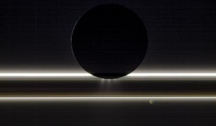 Saturn's moon Enceladus drifts before the rings and the tiny moon Pandora in this view captured by NASA's Cassini spacecraft on Nov. 1, 2009. The Sun provides striking illumination for the icy particles that make up both the rings and the jets.