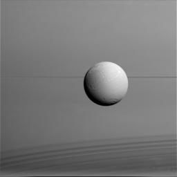 Dione hangs in front of Saturn and its icy rings in this view, captured during NASA's Cassini's final close flyby of the icy moon. North on Dione is up.