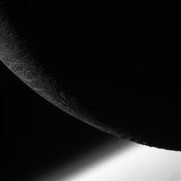 NASA's Cassini orbiter shows its final close flyby of Enceladus to focus on the icy moon's craggy, dimly lit limb, with the planet Saturn beyond.
