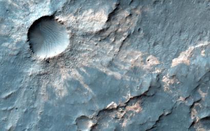 Sandwiched between a crater nearly 4 kilometer across and a much larger and older crater over 15-kilometers in diameter is this small impact crater with light-toned material exposed in its ejecta. This image is from NASA's Mars Reconnaissance Orbiter.