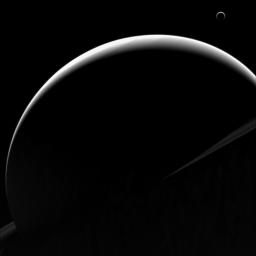 The view from NASA's Cassini orbiter shows Titan's crescent nearly encircling Saturn's disk due to the small haze particles high in its atmosphere refracting the incoming light of the distant Sun.