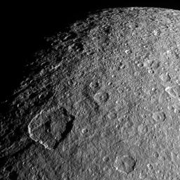 Surface features on Rhea, mostly impact craters in this image from NASA's Cassini spacecraft, are thrown into sharp relief thanks to long shadows.
