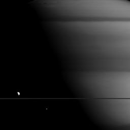 Thanks to the illumination angle, Mimas (right) and Dione (left) appear to be staring up at a giant Saturn looming in the background as captured in this image by NASA's Cassini spacecraft.