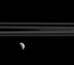 Dione's beautiful wispy terrain is brightly lit alongside Saturn's elegant rings in this image captured by NASA's Cassini spacecraft. The 'wisps' are relatively young fractures on the trailing hemisphere of Dione's icy surface.