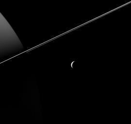 Tethys, dwarfed by the scale of Saturn and its rings, appears as an elegant crescent in this image taken by NASA's Cassini Spacecraft. Views like this are impossible from Earth, where we only see Saturn's moons as (more or less) fully illuminated disks.