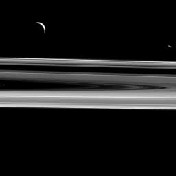 Two moons hover above the rings from this perspective, Enceladus (313 miles or 504 kilometers across), at left, and Janus (111 miles or 179 kilometers across), at right as seen by NASA's Cassini spacecraft.