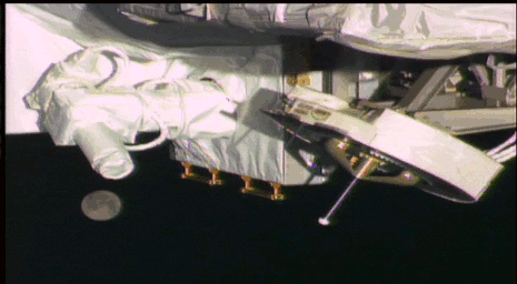 This frame from an animated GIF shows Earth's moon moving below NASA's OPALS laser instrument as seen by a robotic camera on the exterior of the International Space Station.