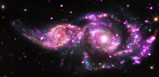 This composite image of NGC 2207 and IC 2163 contains Chandra data in pink, optical-light data from NASA's Hubble Space Telescope in red, green, and blue (appearing as blue, white, orange, and brown), and infrared data from Spitzer Space Telescope in red.
