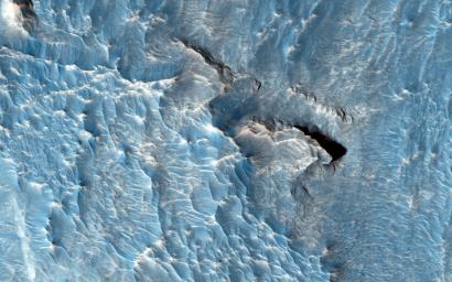 The objective of this observation from NASA's Mars Reconnaissance Orbiter is to examine a light-toned deposit in a region of what is called 'chaotic terrain.' Some shapes suggest erosion by a fluid moving north and south.