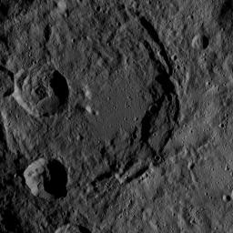 This image of Ceres, taken by NASA's Dawn spacecraft, shows a giant, ancient impact crater with smaller craters in its interior. The large crater shows partial terracing on its southeast rim, whereas the north part is almost fully degraded.