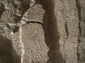 This view shows grains of sand where NASA's Curiosity Mars rover was driven into a shallow sand sheet near a large dune. The disturbance by the wheel exposed interior material of the sand body, including finer sand grains than on the undisturbed surface.