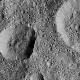 NASA's Dawn spacecraft took this image of unnamed craters in the northern hemisphere of Ceres. The crater at left displays rough spurs of compacted material along its lower edge, while the rest of its rim appears much smoother.