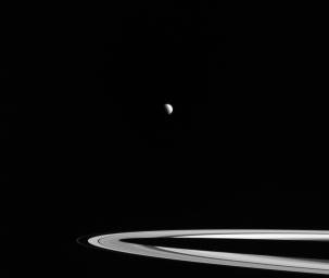 Distant Titan, its northern hemisphere drenched in the sunlight of late spring, hangs above Saturn's rings in this image captured by NASA's Cassini spacecraft.