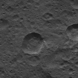 This picture from NASA's Dawn spacecraft shows craters near the equator of Ceres. Faint patches and streaks of bright material can be seen in various parts of the scene. The two largest craters have streaks of material on their walls.