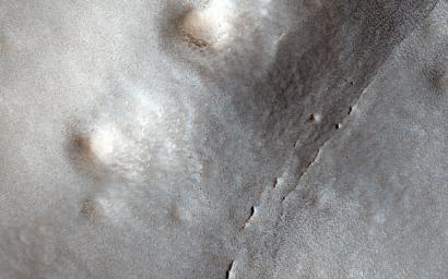 This image from NASA's Mars Reconnaissance Orbiter shows many small craters over a larger degraded one in the northern lowlands. These small craters are smoother and shallower than their counterparts closer to the equator.