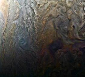 This enhanced-color image from NASA's Juno spacecraft of a mysterious dark spot on Jupiter seems to reveal a Jovian 'galaxy' of swirling storms.