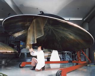 This archival photo shows an engineer working on the construction of a large, dish-shaped, high-gain antenna on NASA's Voyager. The picture was taken on July 9, 1976.